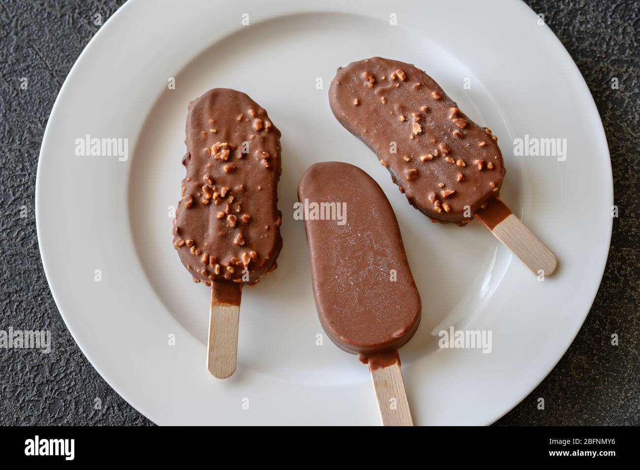 Chocolate-covered vanilla ice cream bars on the white plate Stock Photo