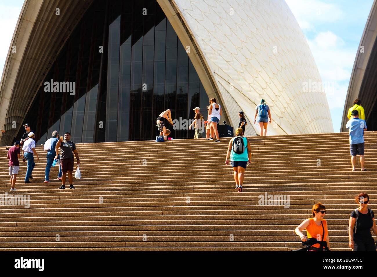 Tourists are posing for photos at Sydney Opera House, a female tourist doing an acrobatic underarm stand. Sydney, New South Wales, Australia. Stock Photo