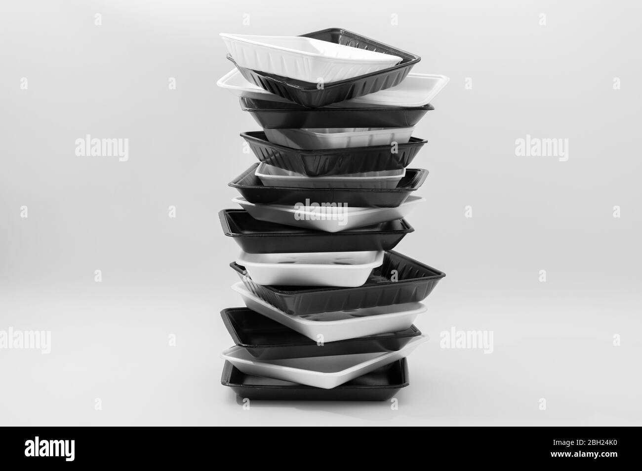 White and black foam food container trays (Styrofoam trays) stacked. Isolated on white background. Close-up. Copy space. Horizontal shot. Stock Photo