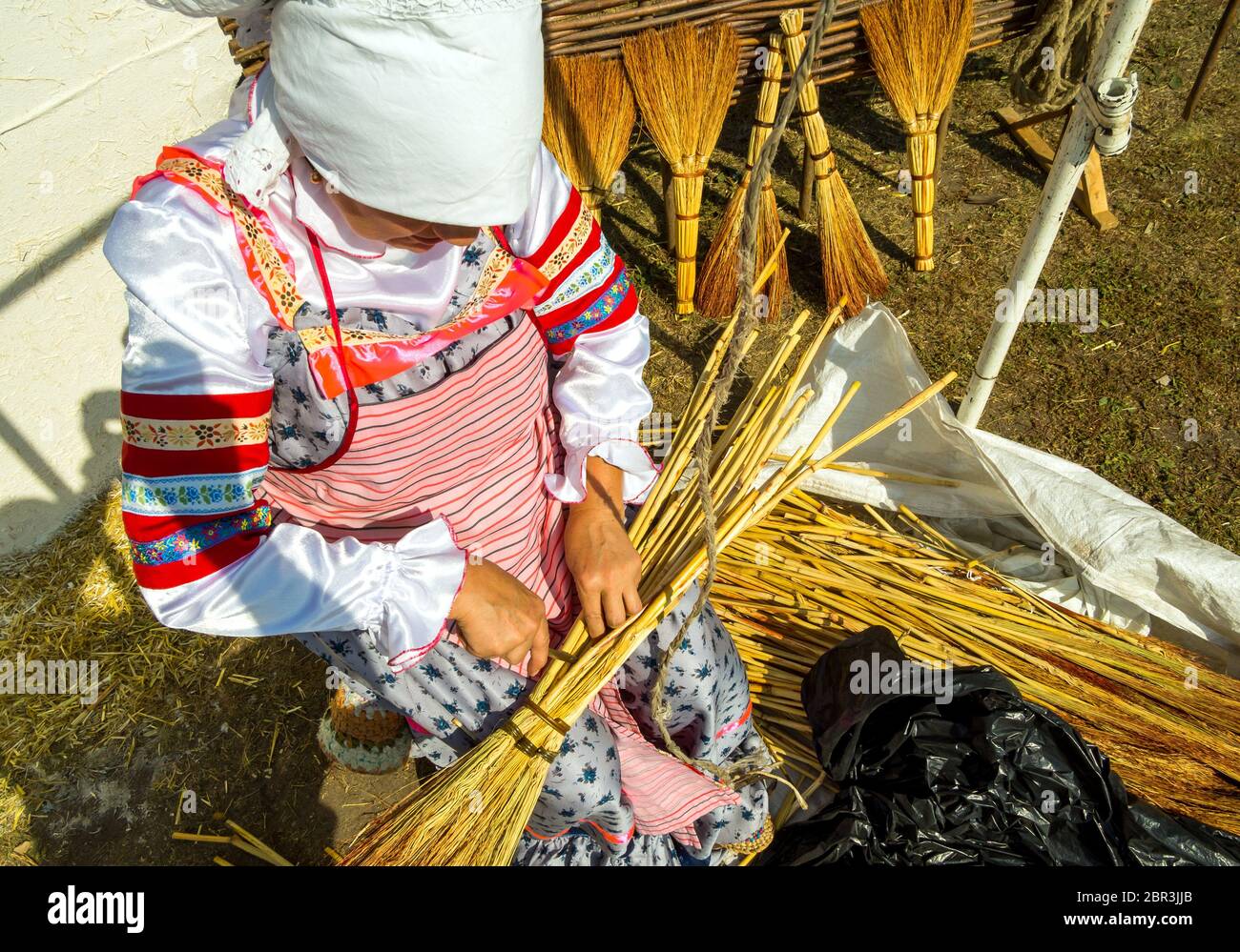 Voronezh, Russia - September 5, 2019: Woman in national Russian costume knits brooms Stock Photo