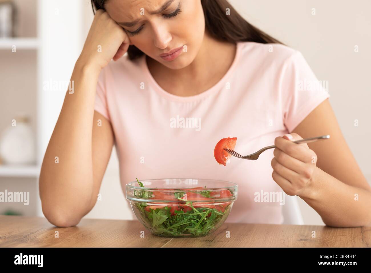 Sad Woman Eating Salad Slimming Sitting At Table At Home Stock Photo