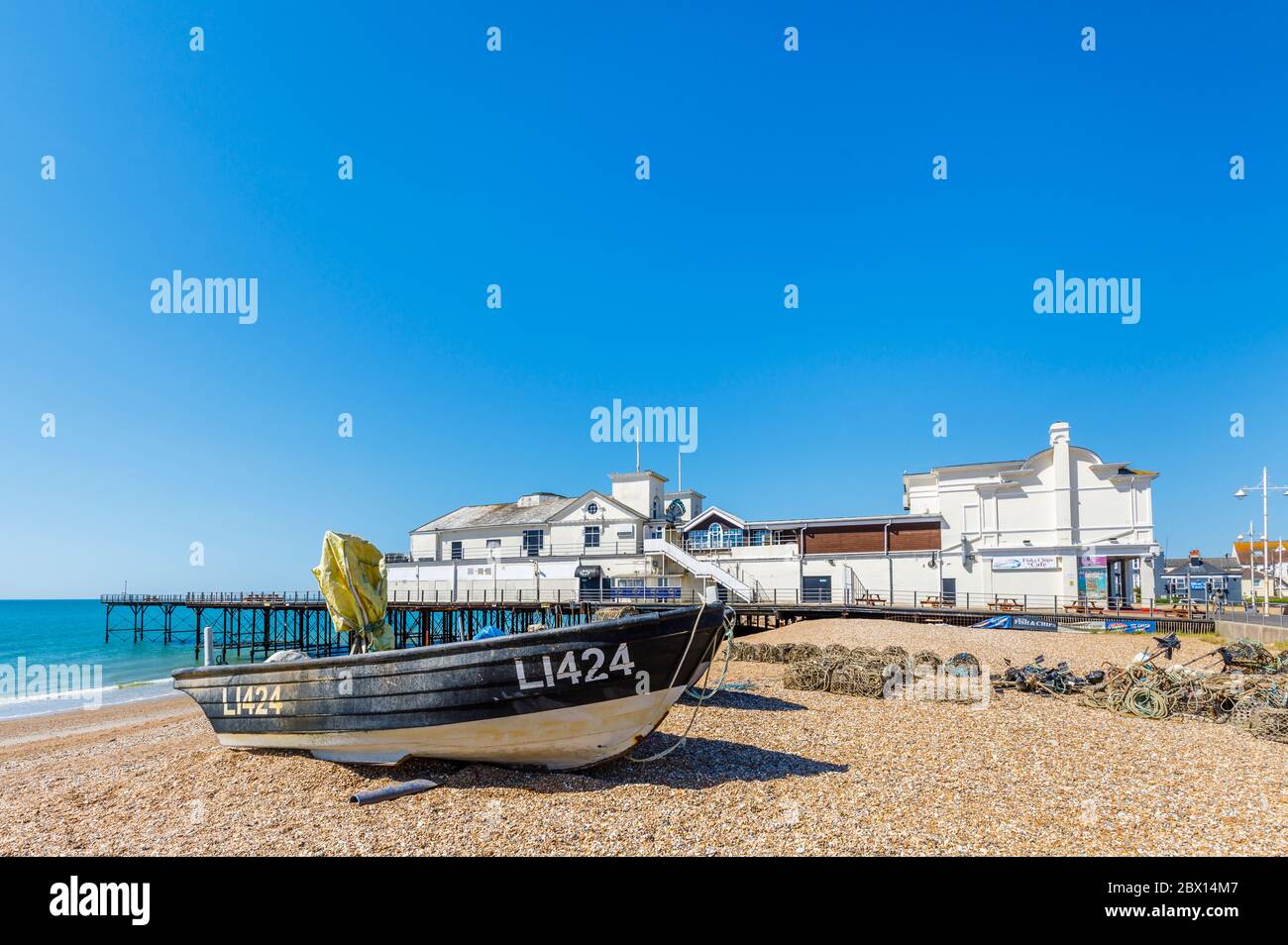 A fishing boat on the stony shingle beach by the pier on the seafront at Bognor Regis, a seaside town in West Sussex, south coast England Stock Photo