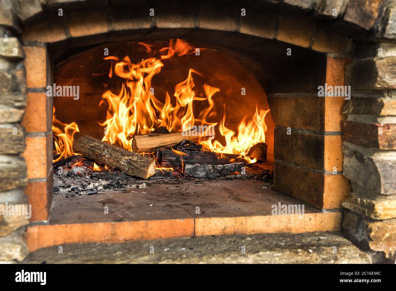 Old stone homemade pizza oven. Fire in the furnace. Homemade baking pizza. Bakery. Traditional Italian food. Stock Photo