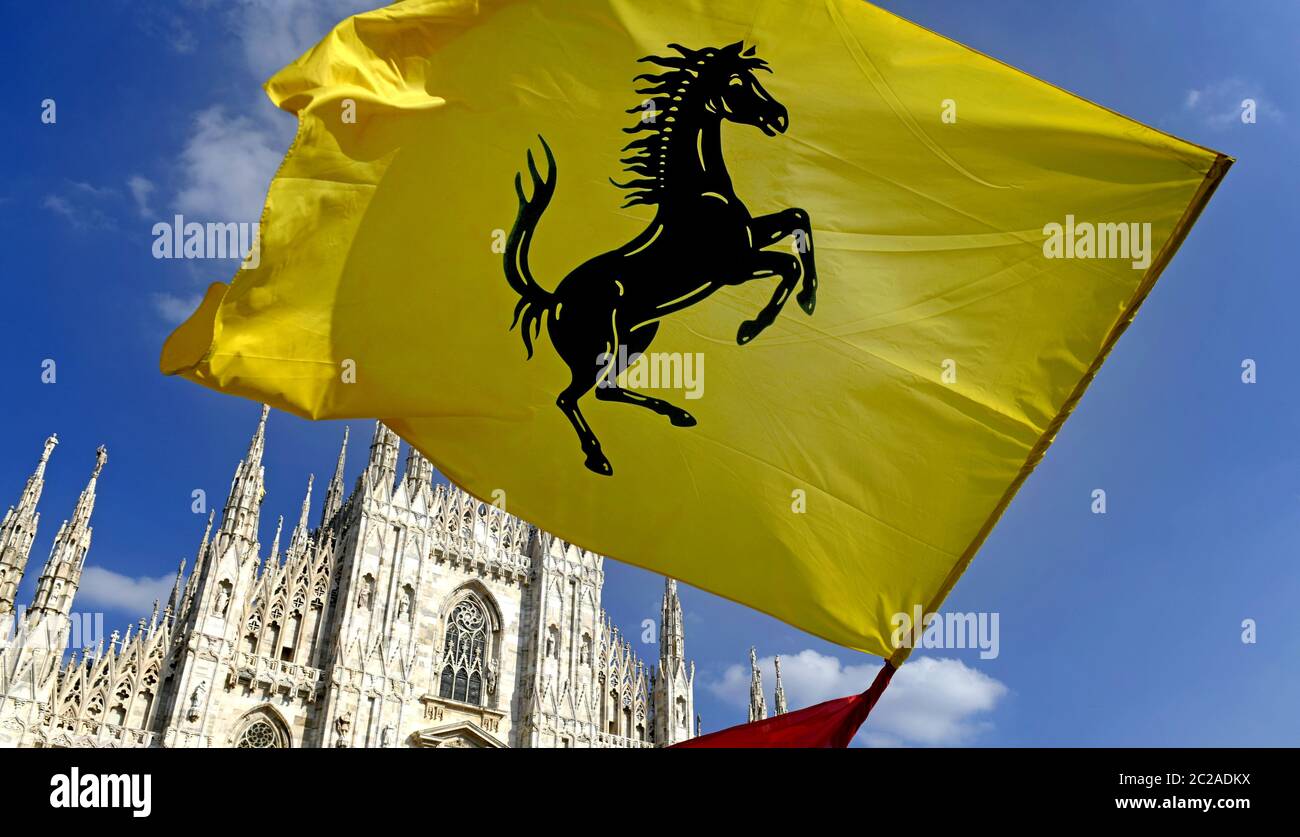 Ferrari fans waving a Ferrari flag in Duomo square to celebrate the 90th anniversary of the Ferrari , in Milan. Stock Photo