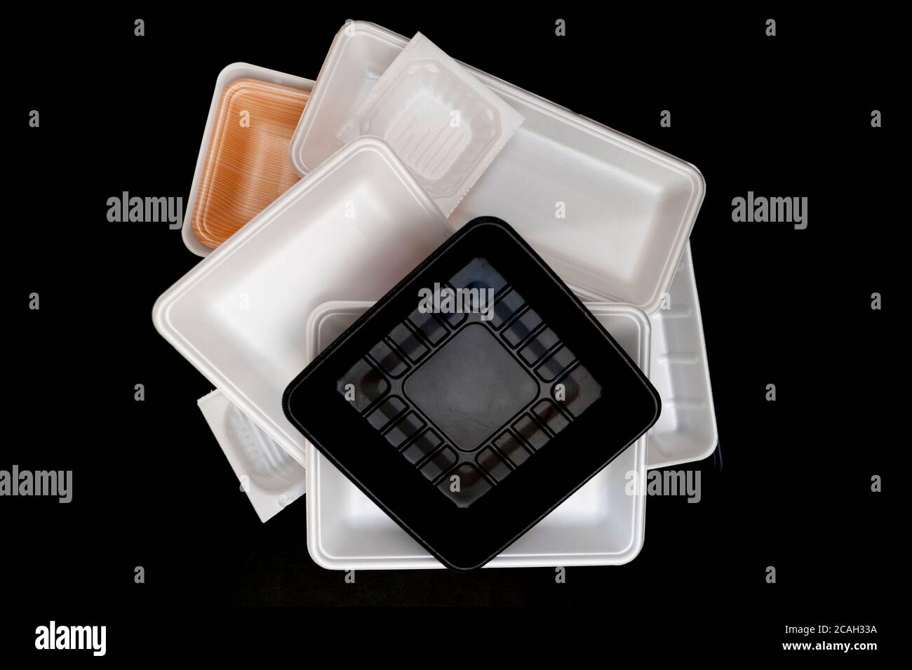 Foam food container tray (Styrofoam tray). Various Styrofoam trays of colors: orange, white and black isolated on black background. Horizontal shot. Stock Photo