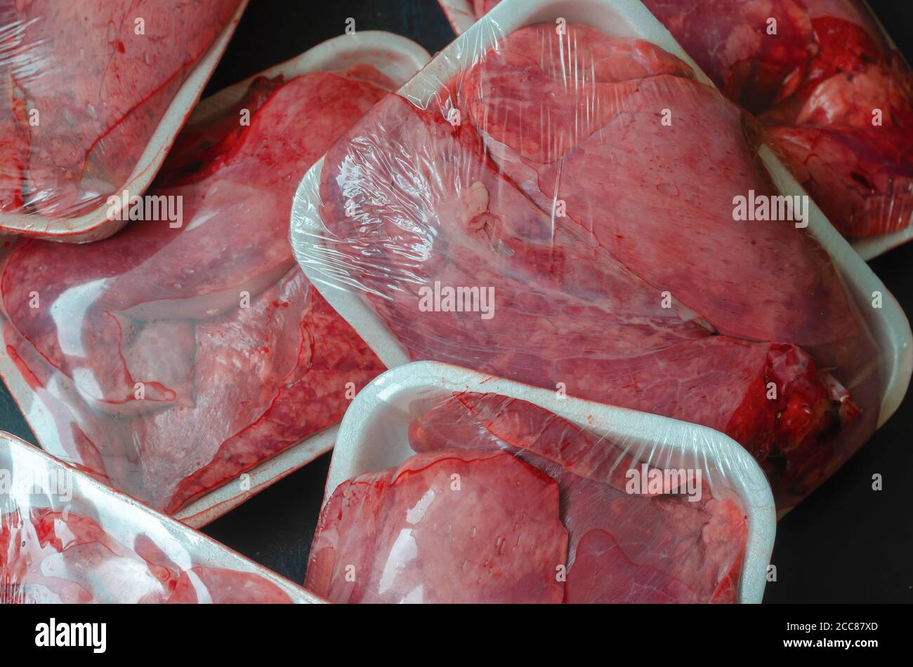 Raw beef lung portions background. Meat offal close-up. White trays with fresh meat. Copy space. Stock Photo