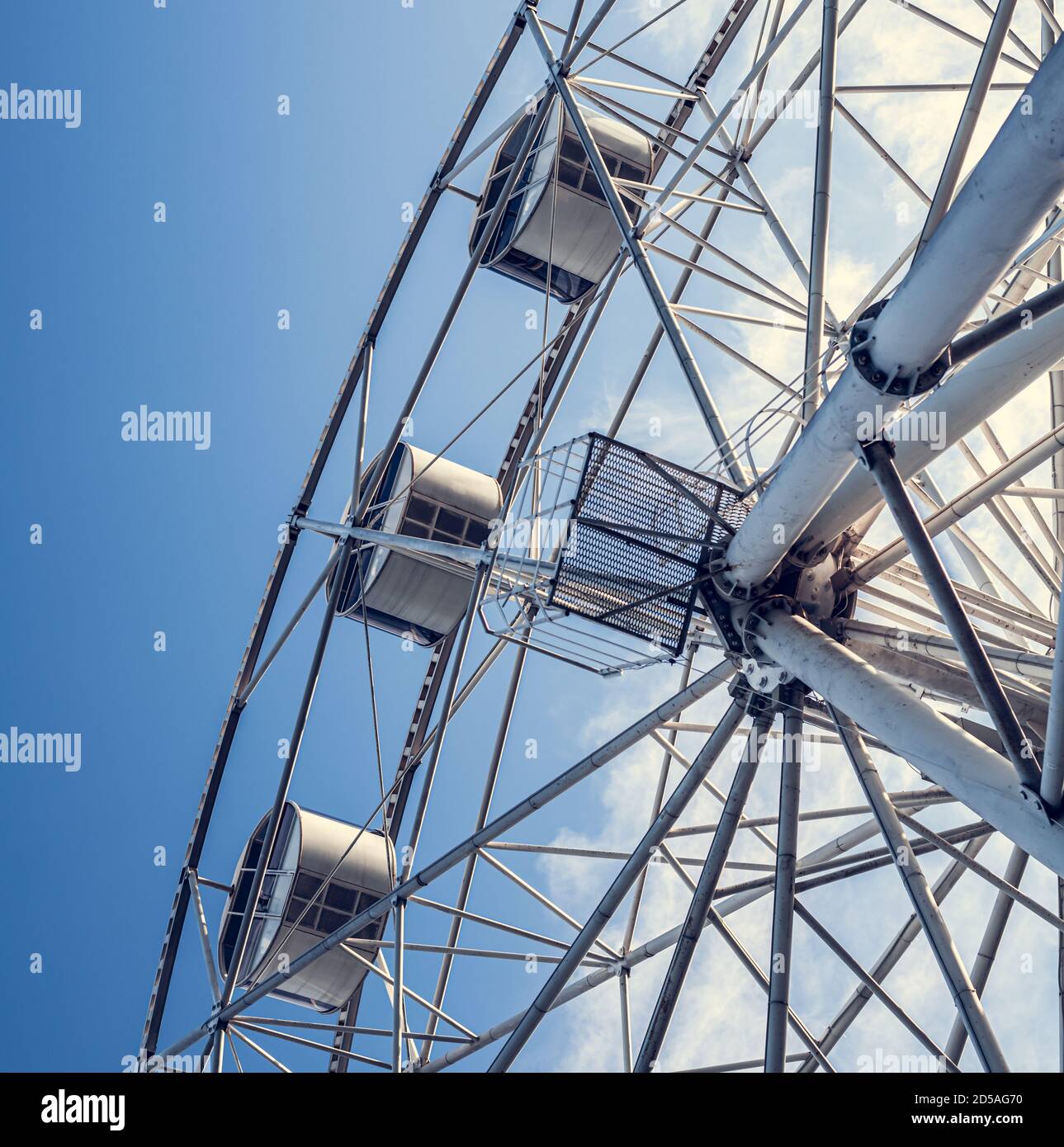 Gray or white metal ferris wheel with closed passenger cabins close-up in the amusement park in the afternoon Stock Photo