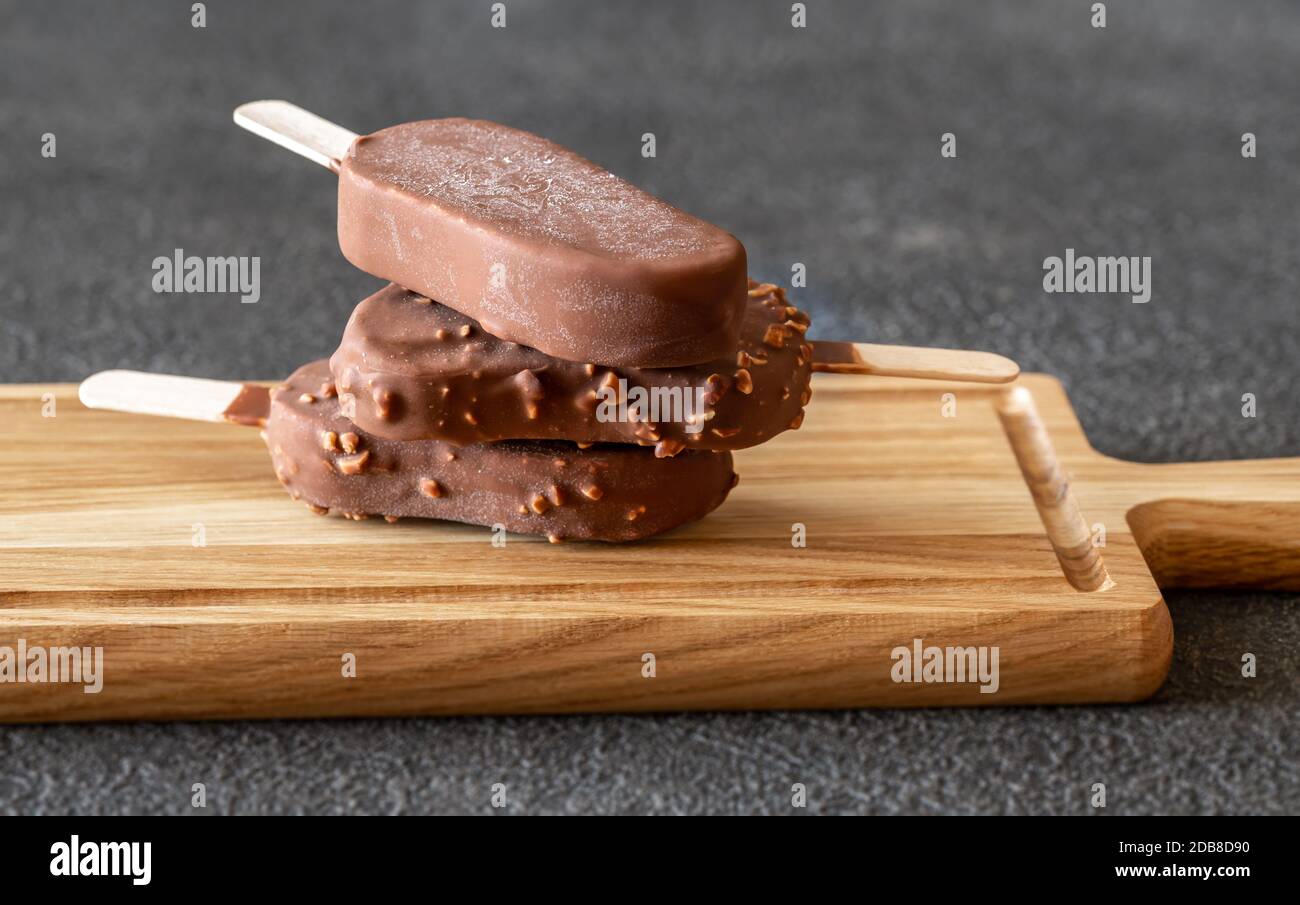 Chocolate-covered vanilla ice cream bars on the wooden board Stock Photo