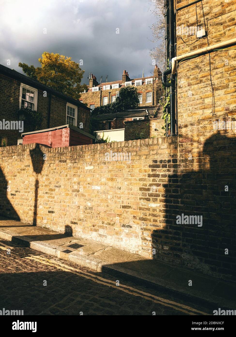 Terraced houses of New End, Hampstead, London at sunset with shadow of an old fashioned street lamp. Stock Photo