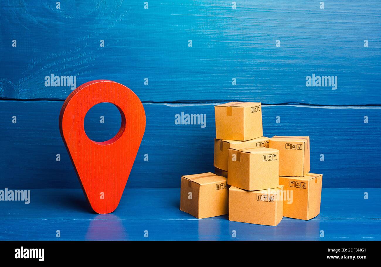 Red location pin pointer symbol and cardboard boxes. Improving the efficiency, speed and low cost of delivering goods to consumer. Business adaptation Stock Photo