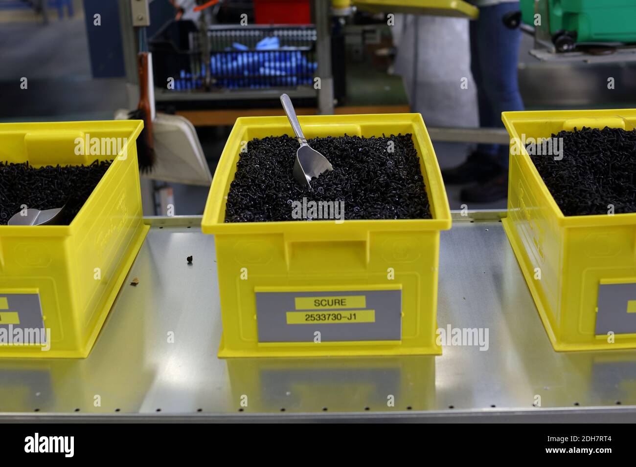 Yellow boxes with many small screws and metal scoop Stock Photo