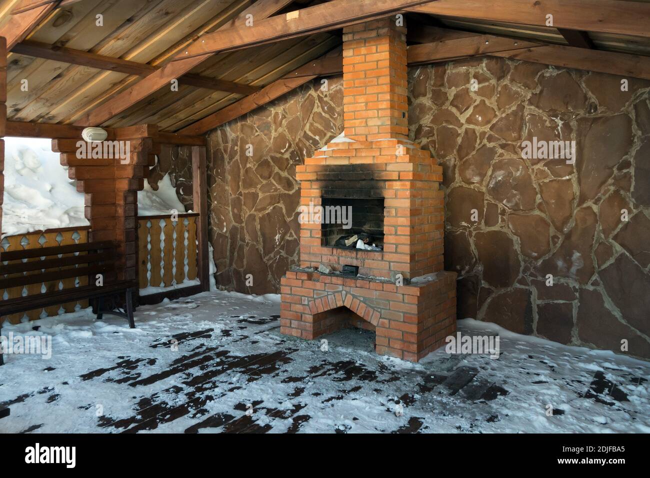 A specially equipped place for winter recreation with a brick fireplace under the roof. Stock Photo