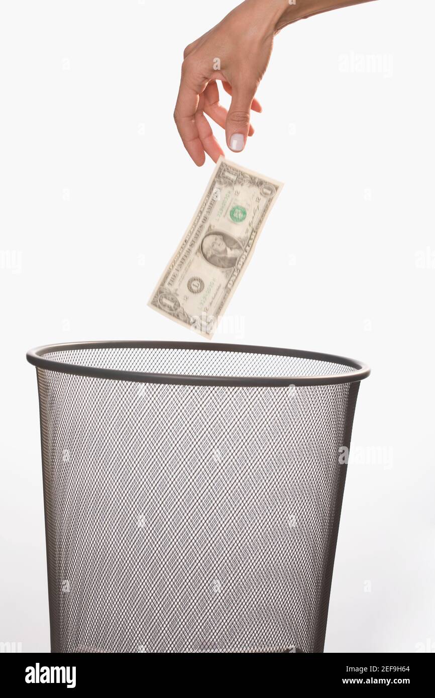 Close up of a personÅ½s hand throwing a US dollar bill in a garbage bin Stock Photo