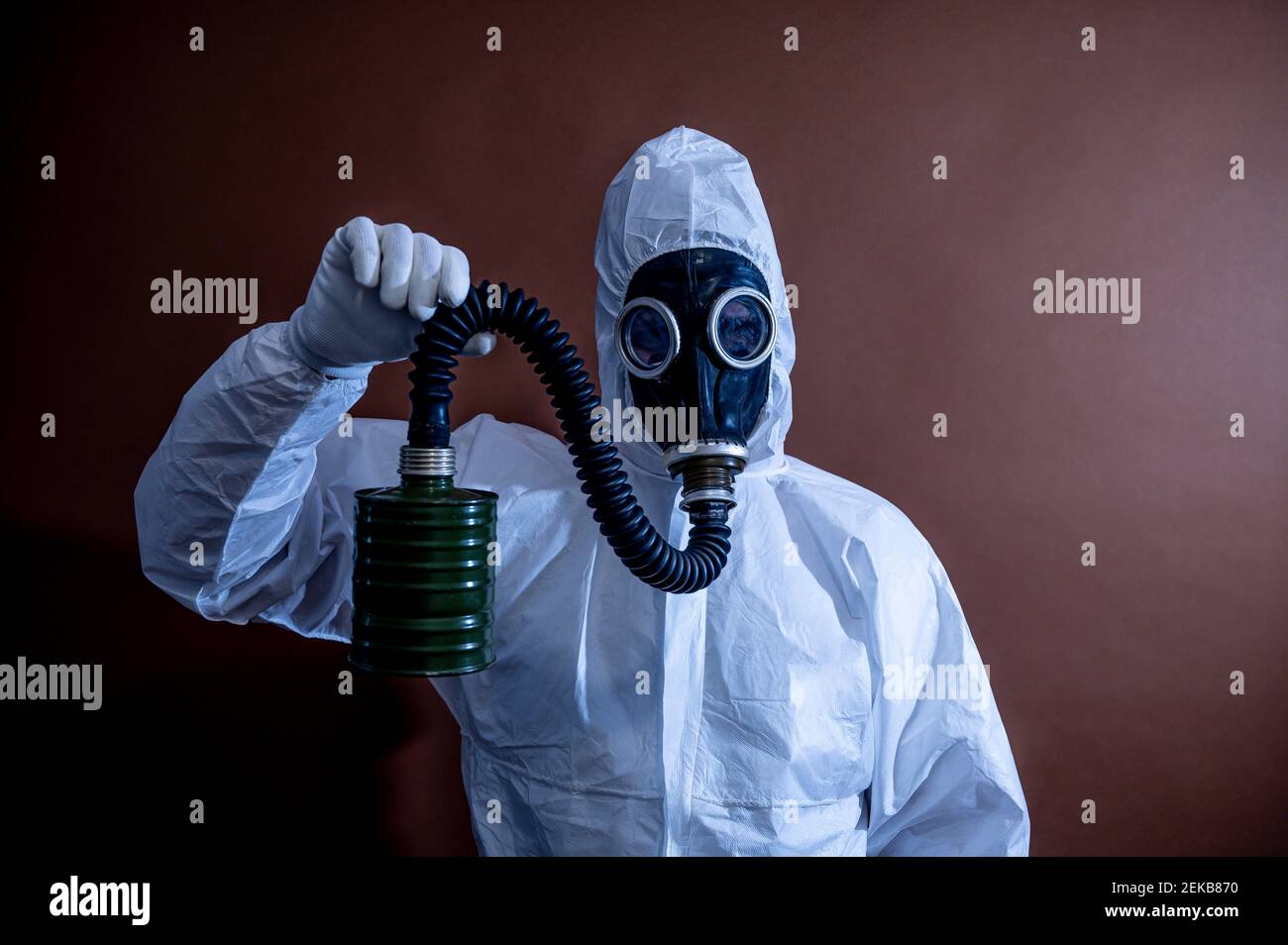 Mature in protective coveralls holding pipe of gas mask Stock Photo