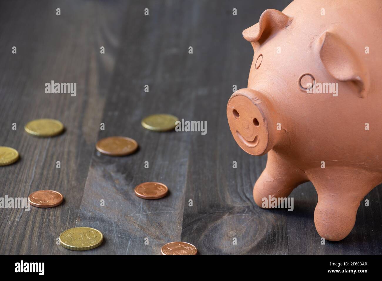 Top view of half clay piggy bank, on wooden table with euro coins, horizontal, with copy space Stock Photo