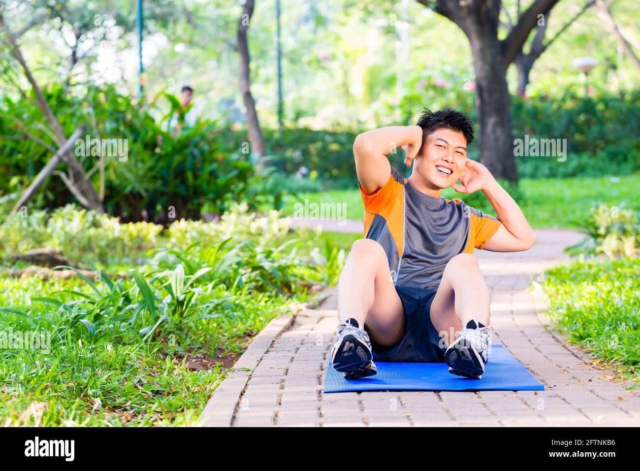 Asian man doing crunches for six pack training in park Stock Photo