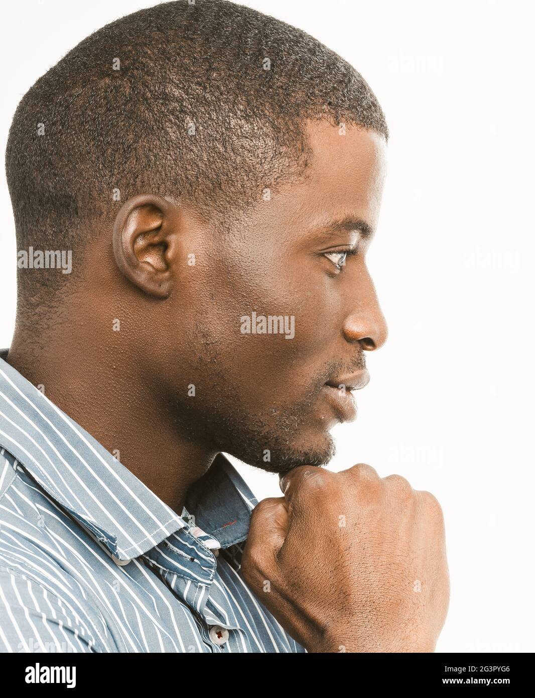 Thoughtful African American man touches his chin looking to the side. Profile view of short-haired handsome guy on white backgro Stock Photo