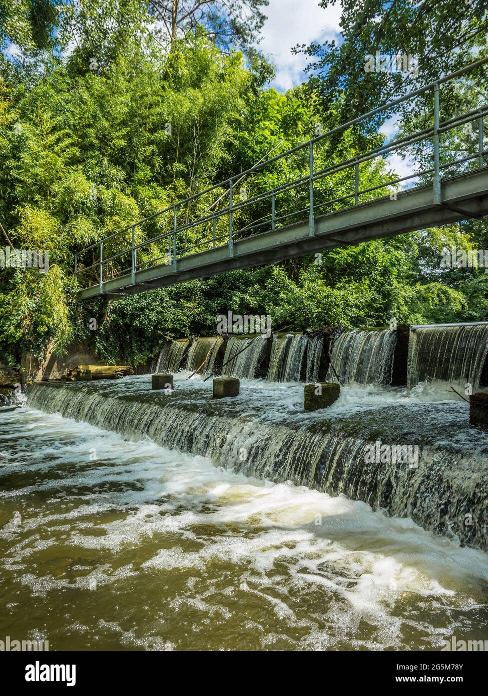 Man-made waterfall / weir and footbridge across the river Claise near Mezieres-en-Brenne, Indre (36), France. Stock Photo