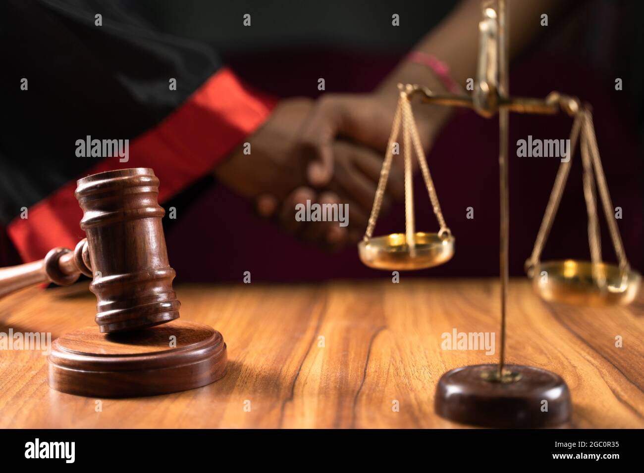 Focus on gavel, concept of judicial corruption showing by judge making deal in background by shaking hands. Stock Photo