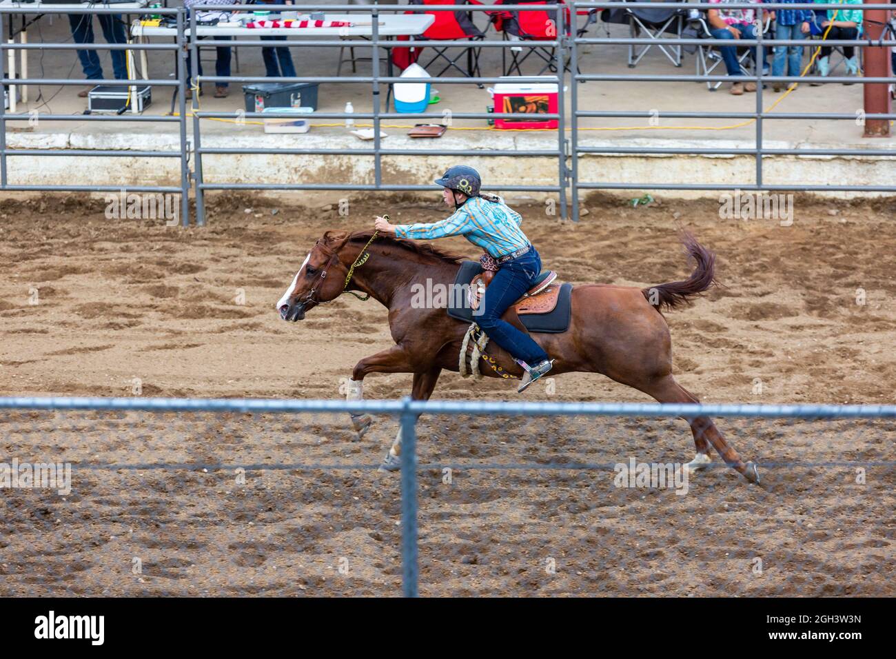 A cowgirl rides her horse through the barrel race event during a rodeo event at the Noble County Fairgrounds in Kendallville, Indiana, USA. Stock Photo