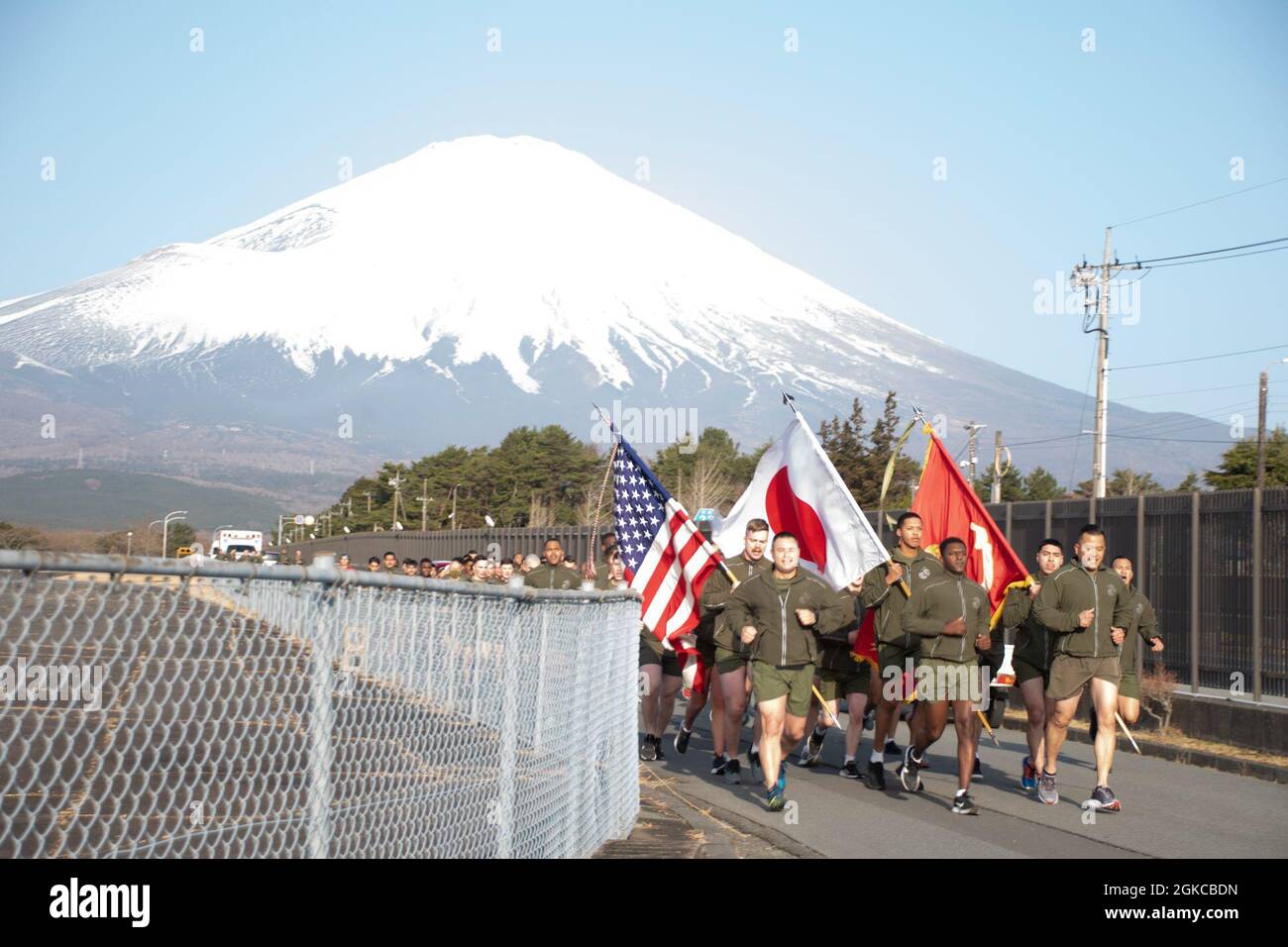 Combined Arms Training Center Camp Fuji service members and civilian personnel run in formation bearing the U.S. and Japan flags, Gotemba, Japan, March 11, 2021.  The installation held a remembrance run for the 10th year anniversary of the 2011 Great East Japan Earthquake, and the tsunami and reactor disaster that followed, and later in the day observed a moment of silence held across the country. Stock Photo