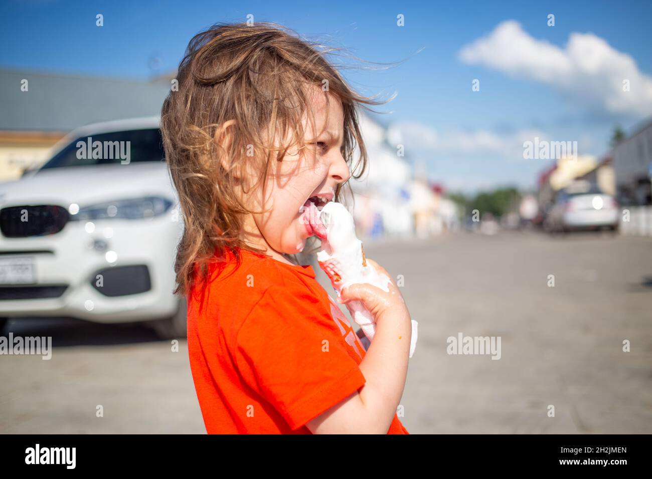 Caucasian girl eating ice cream outdoors hot summer day. ice cream melts and flows Stock Photo