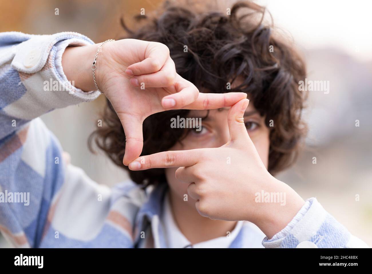 Young brunette woman with curly hair making the Framing sign with her hands Stock Photo