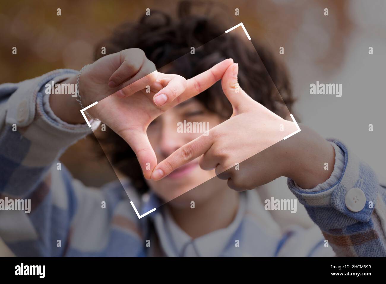 Young brunette woman with curly hair making the Framing sign with her hands Stock Photo