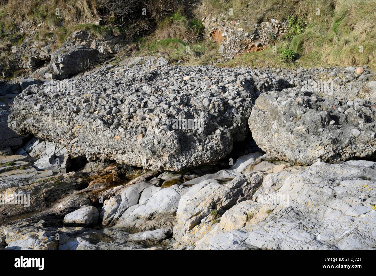 Raised Beach showing ancient higher sea levels where beach formed by concretion of sandy layers overlain with rounded pebbles, shells and breccia Stock Photo