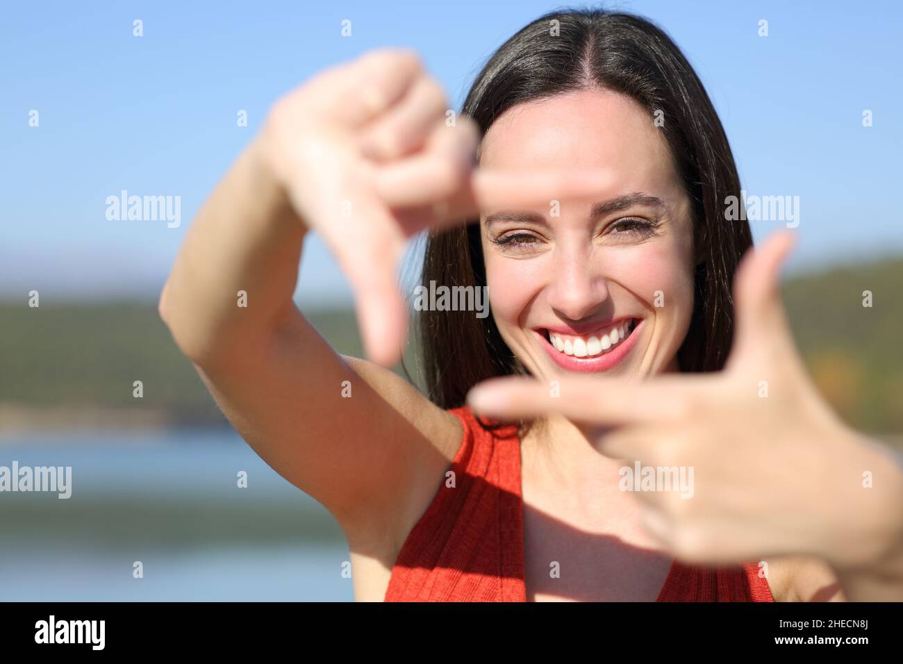 Front view portrait of a happy woman smiling framing with hands at camera Stock Photo