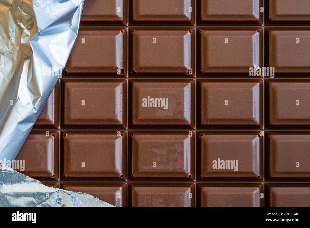 Chocolate bar with part of the silver wrapper. Stock Photo