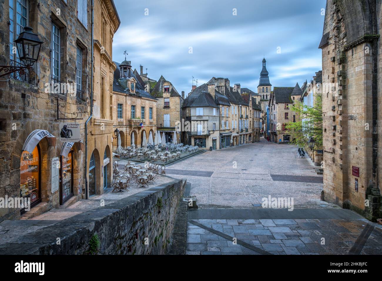 Sarlat main square with no people with illuminated shops and Sarlat cathedral at sunrise Sarlat Dordogne France Stock Photo