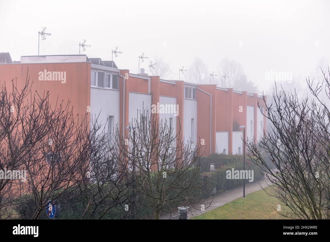 Row of modern terraced houses shrouded in fog in winter Stock Photo