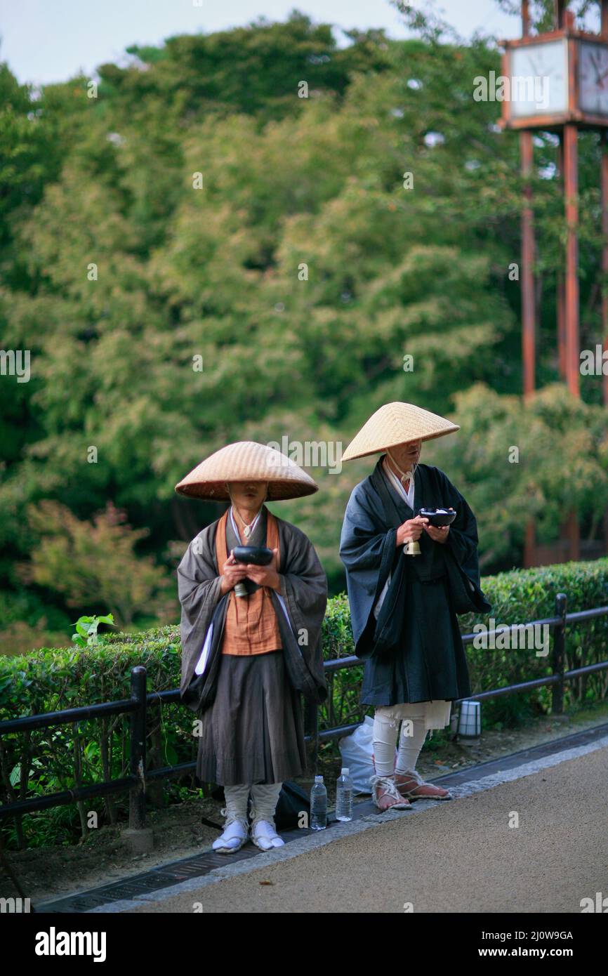 Buddhist monks practice takuhatsu chanting sutras and collecting donations in Kyoto street. Japan Stock Photo