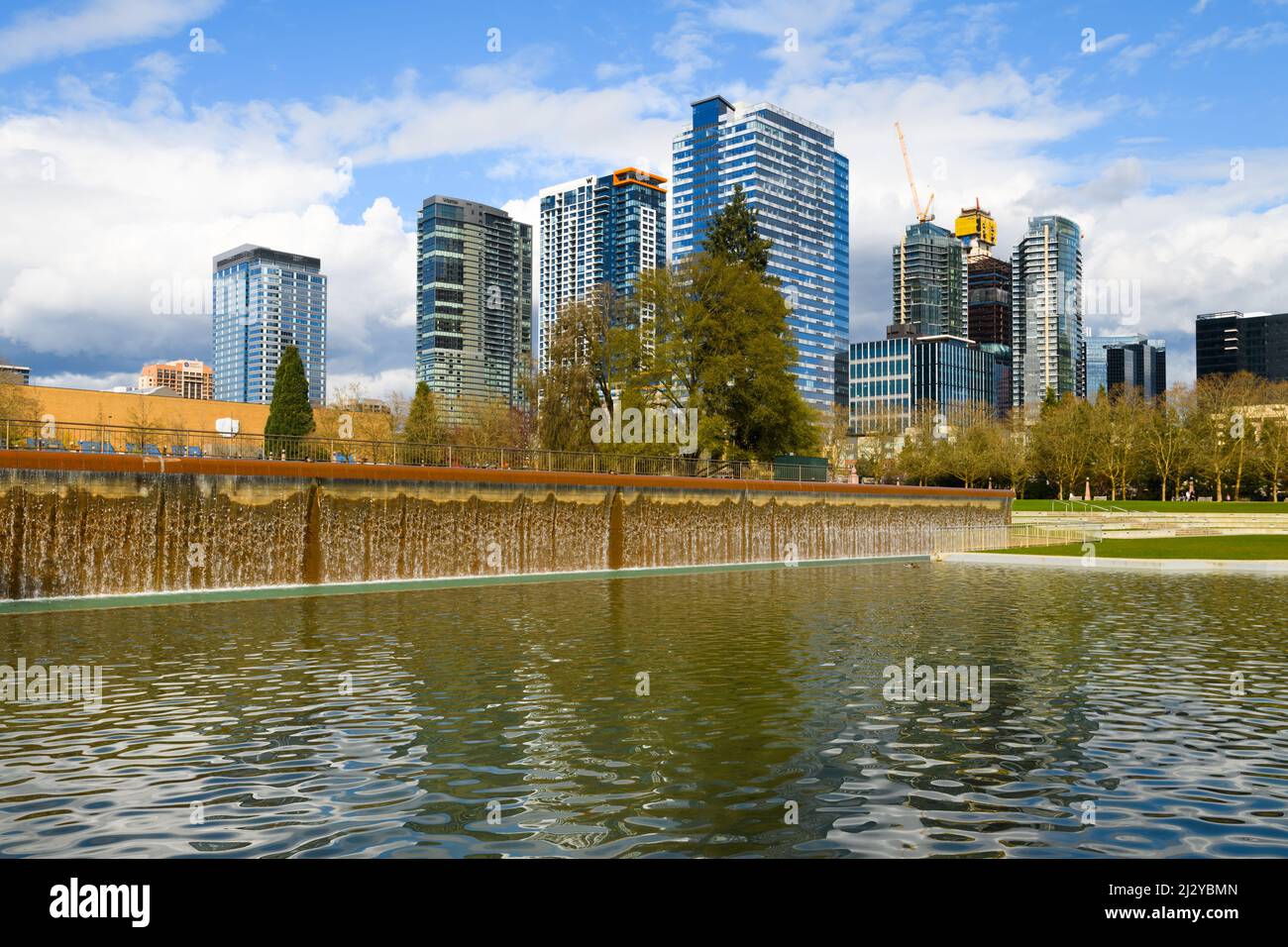 Bellevue, WA, USA - March 31, 2022; Waterfall in Downtown Park in Bellevue in front of the modern city skyline and puffy clouds in Spring Stock Photo