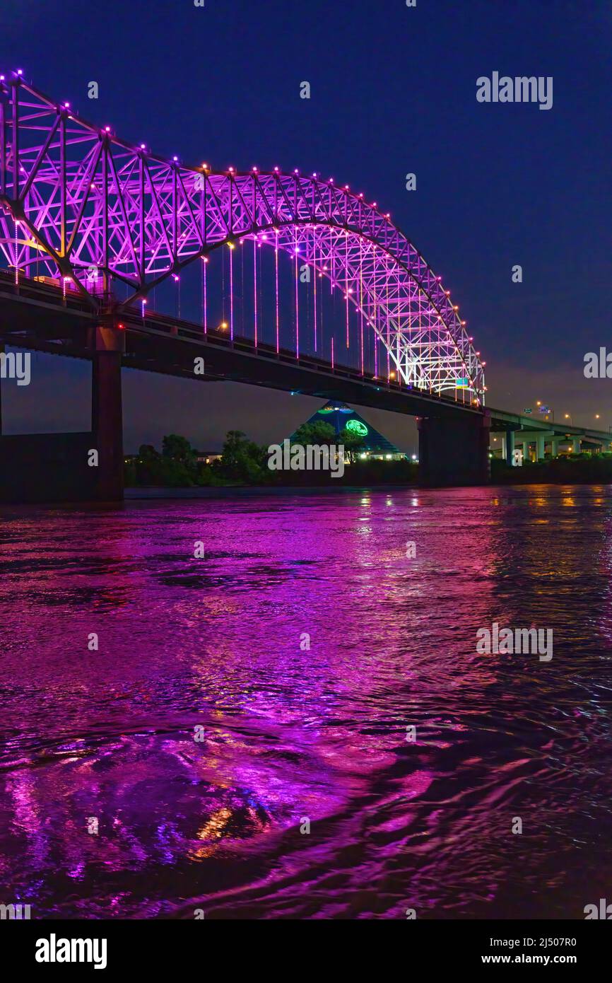 The Hernando de Soto Bridge’s nighttime reflection seen at dusk from the Memphis Queen cruising on the Mississippi River in Tennessee. Stock Photo