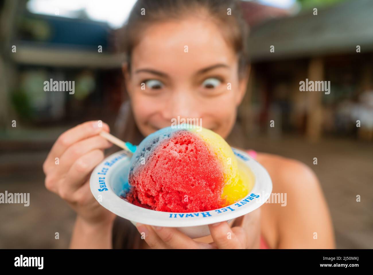 Hawaiian shave ice happy woman tourist making funny face hungry eating sweet frozen snow cone local dessert food of Hawaii Stock Photo