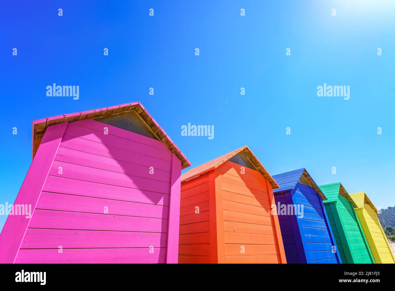 Vibrant colourful wooden huts against clear blue sky with copy space Stock Photo