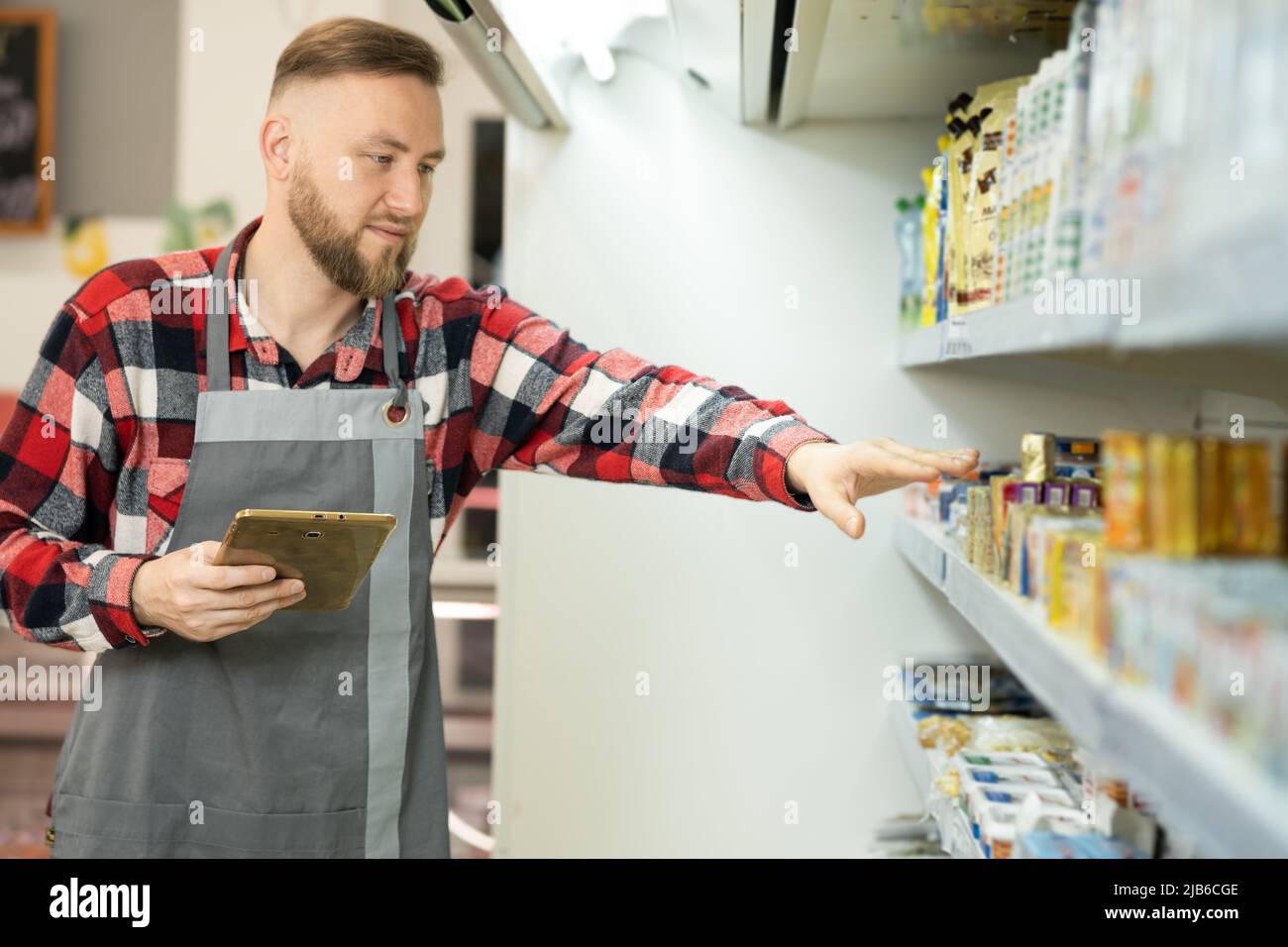 Supermarket clerk using apps on a digital tablet, handsome supervisor with tablet pc in the mall, innovative technology and work. Retail Stock Photo