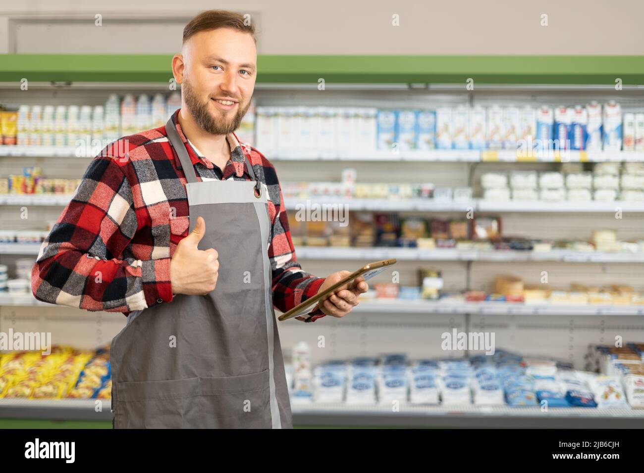 supermarket clerk using apps on a digital tablet, innovative technology and work concept, close up, young handsome supervisor with tablet pc in the Stock Photo