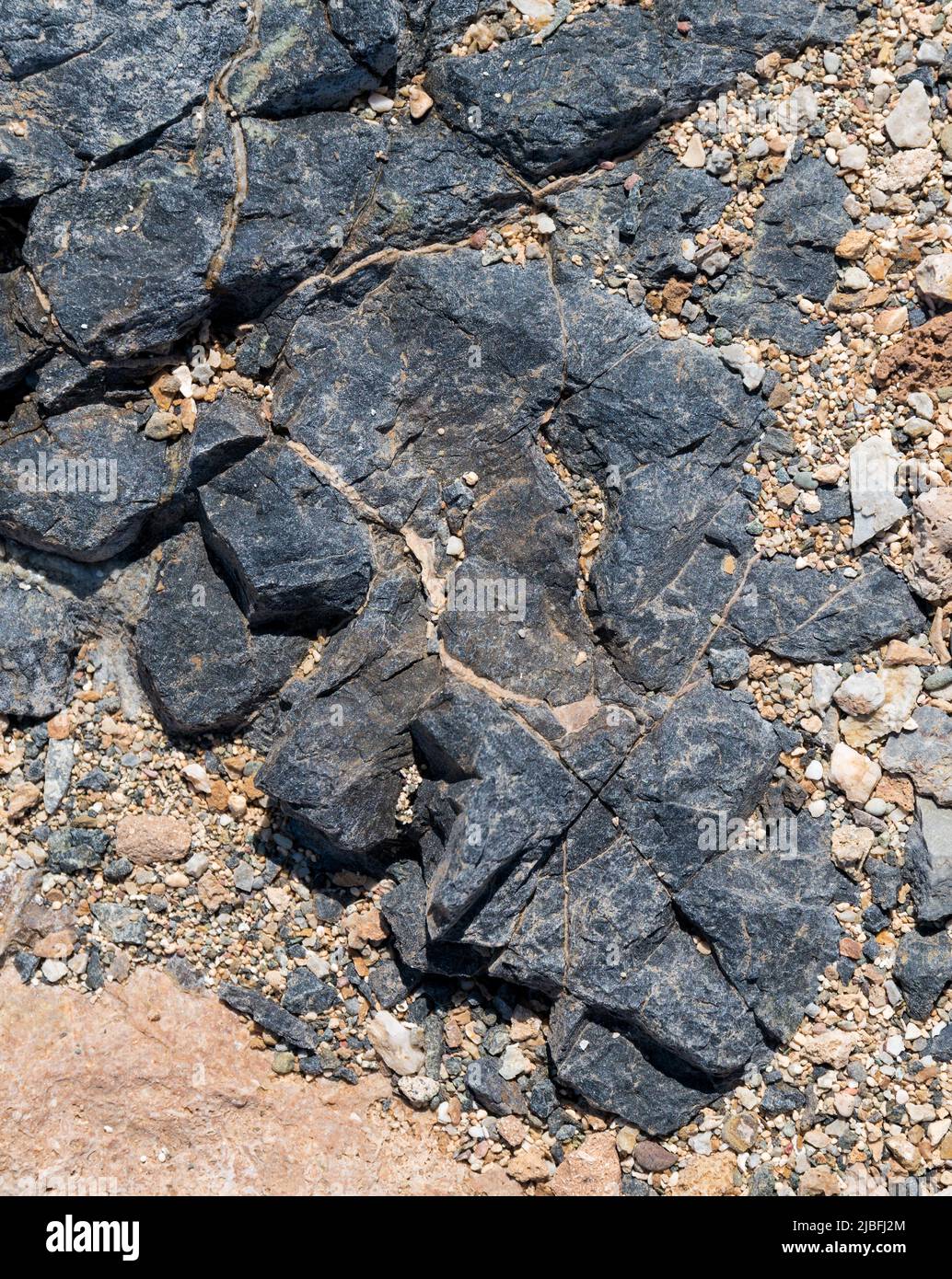 Beautiful black rock formation on the yellow-orange sandy beach. Abstract. Chrissi island, Crete, Greece Stock Photo