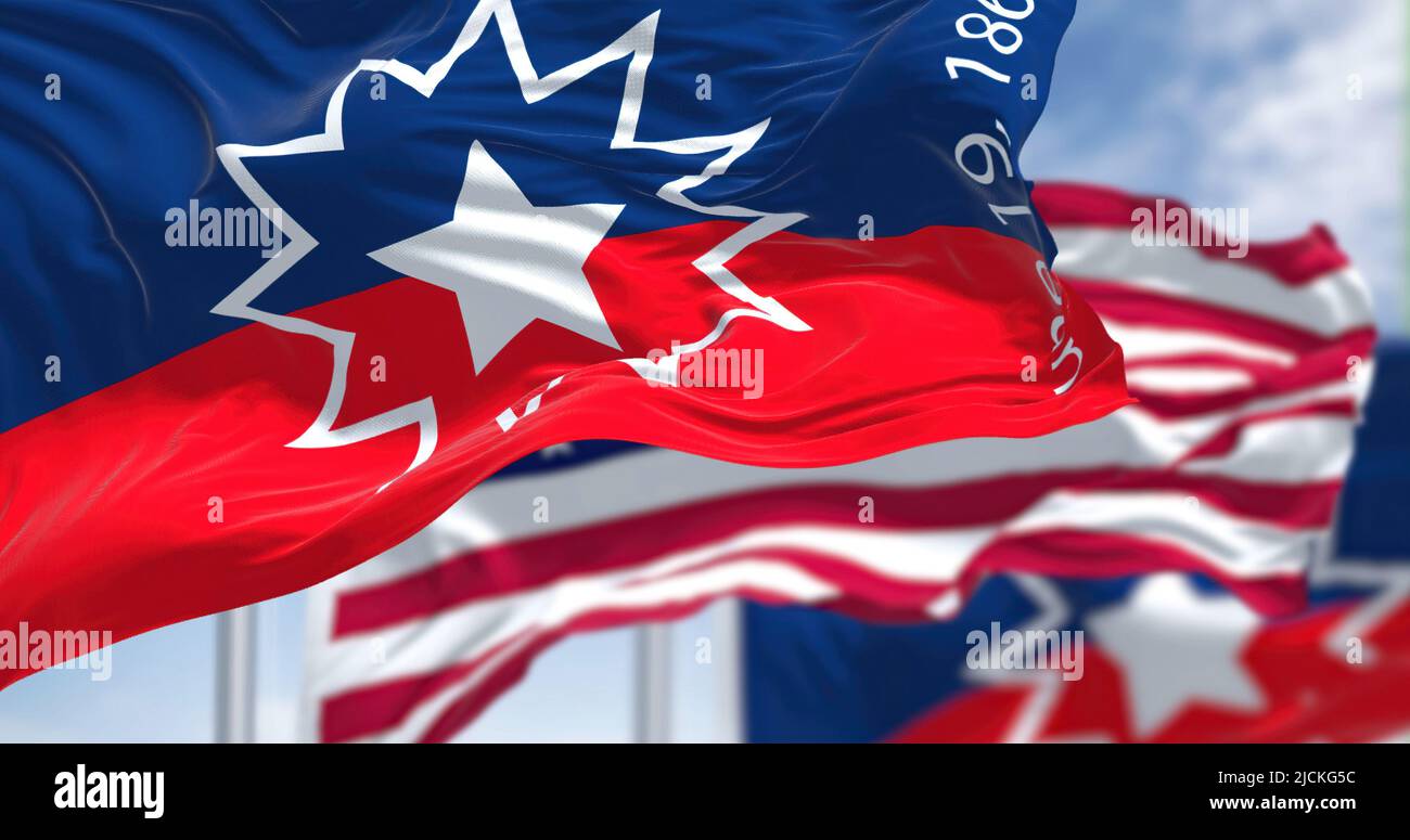 The Juneteenth flag waving in the wind with the american flag. Juneteenth is a federal holiday in the United States commemorating the emancipation of Stock Photo