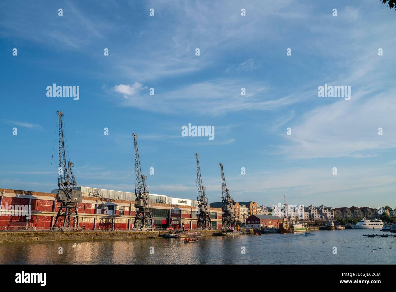 Cranes, rowing boats, and the mShed in the floating harbour harbourside area of Bristol on a sunny summer evening. Stock Photo