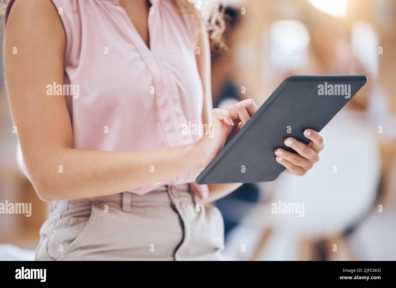 Close up of a business womans hands browsing on a digital tablet in an office. One female only using the internet online and downloading apps for Stock Photo