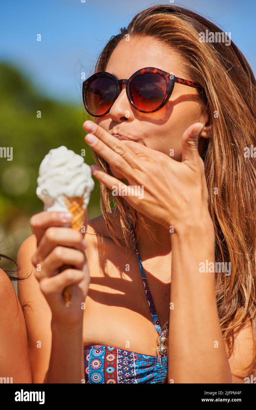 You have to treat yourself. Shot of a beautiful young woman enjoying an ice cream cone. Stock Photo