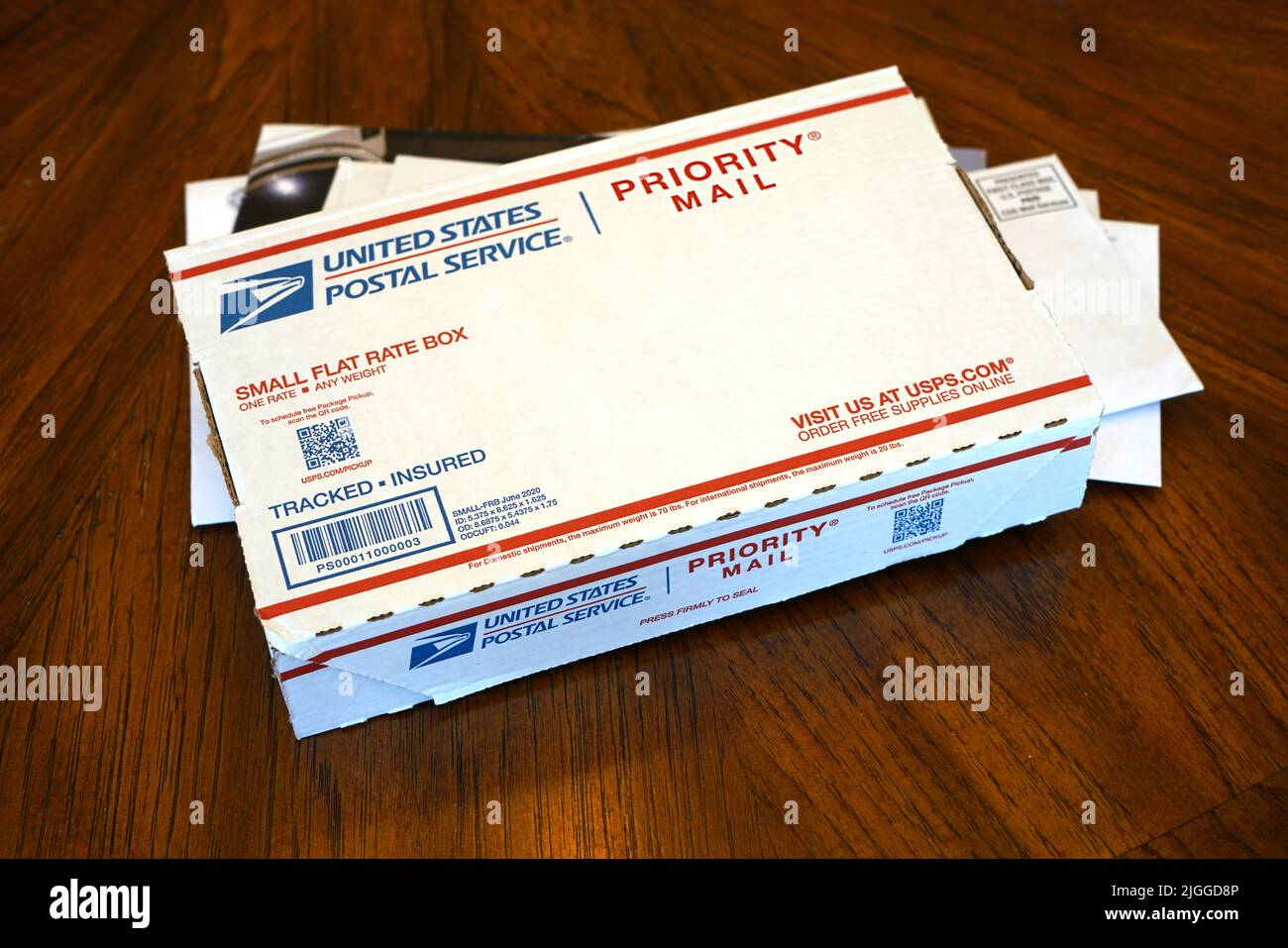 Lake Elsinire, CA, USA - July 9, 2022: USPS Priority Mail package on stack of daily mail. Stock Photo