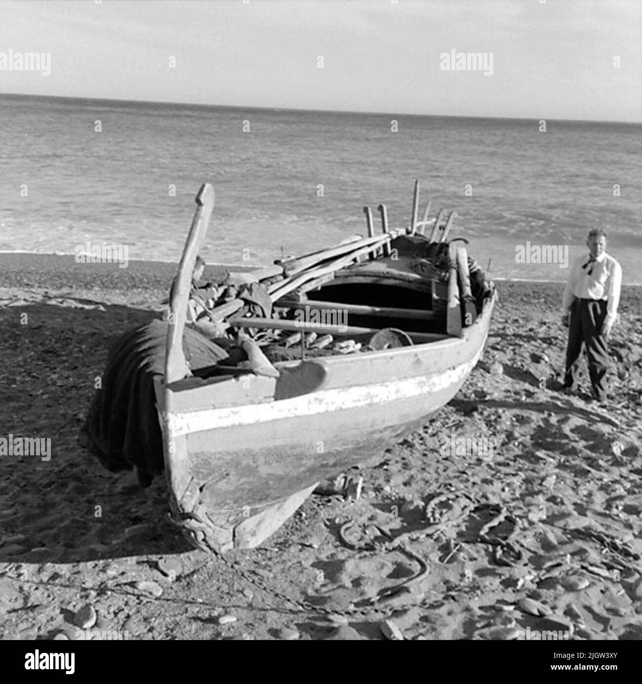 41. Spain. Photo journal is available at B.M.A. + Photo albums. Acquisition: Books and archive materials. Photos taken 1959-11-12.12 Pictures in series. According to notes: Spain. S. Mediterranean coast, Castell de Ferro, 12/11-59. Old -fashioned boat on the beach. One stands looking at a boat that is commissioned on a sandy beach. Stock Photo