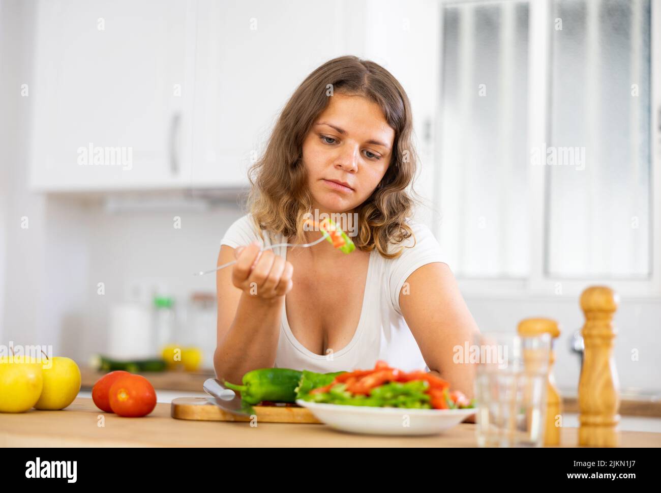 Portrait of sad woman eating salad at home Stock Photo