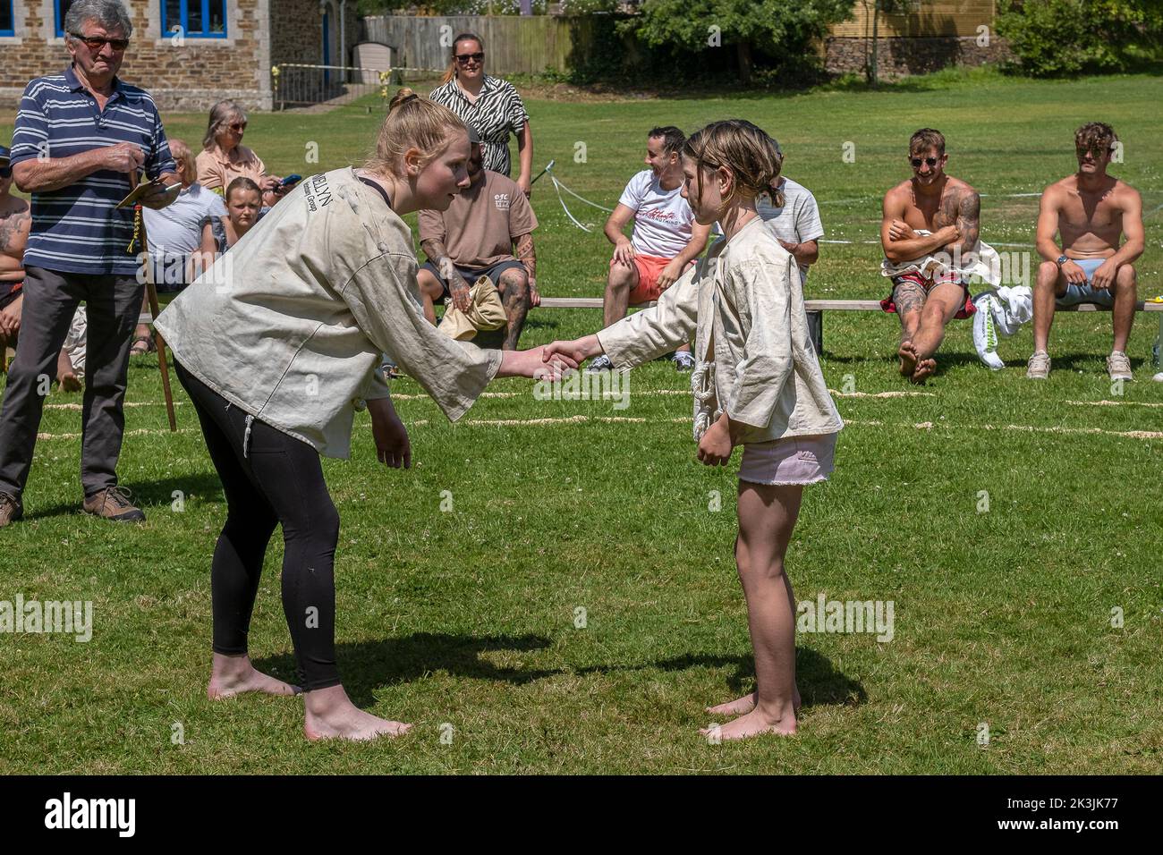 A judge referee stickler watching two young girls shaking hands at that start of their bout in the Grand Cornish Wrestling Tournament on the picturesq Stock Photo