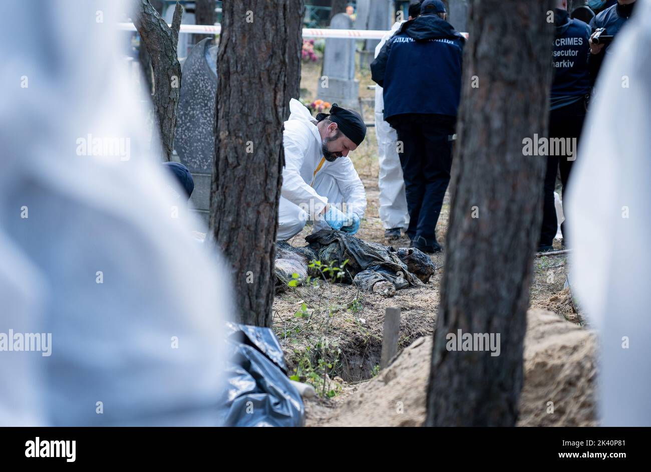 (EDITORS NOTE: Image depicts death)An investigator wearing protective gear is seen examining an exhumed body. A mass burial site was found in the outskirt of the eastern Ukrainian city, Izyum, Kharkiv region which has been liberated from Russian occupation two weeks ago. At least 445 new graves were found in the site of an existing cemetery while many only have numbers written on the wooden cross. All bodies will be exhumed and sent for forensic examination but it was told from initial investigations that some bodies shown sign of torture. Stock Photo